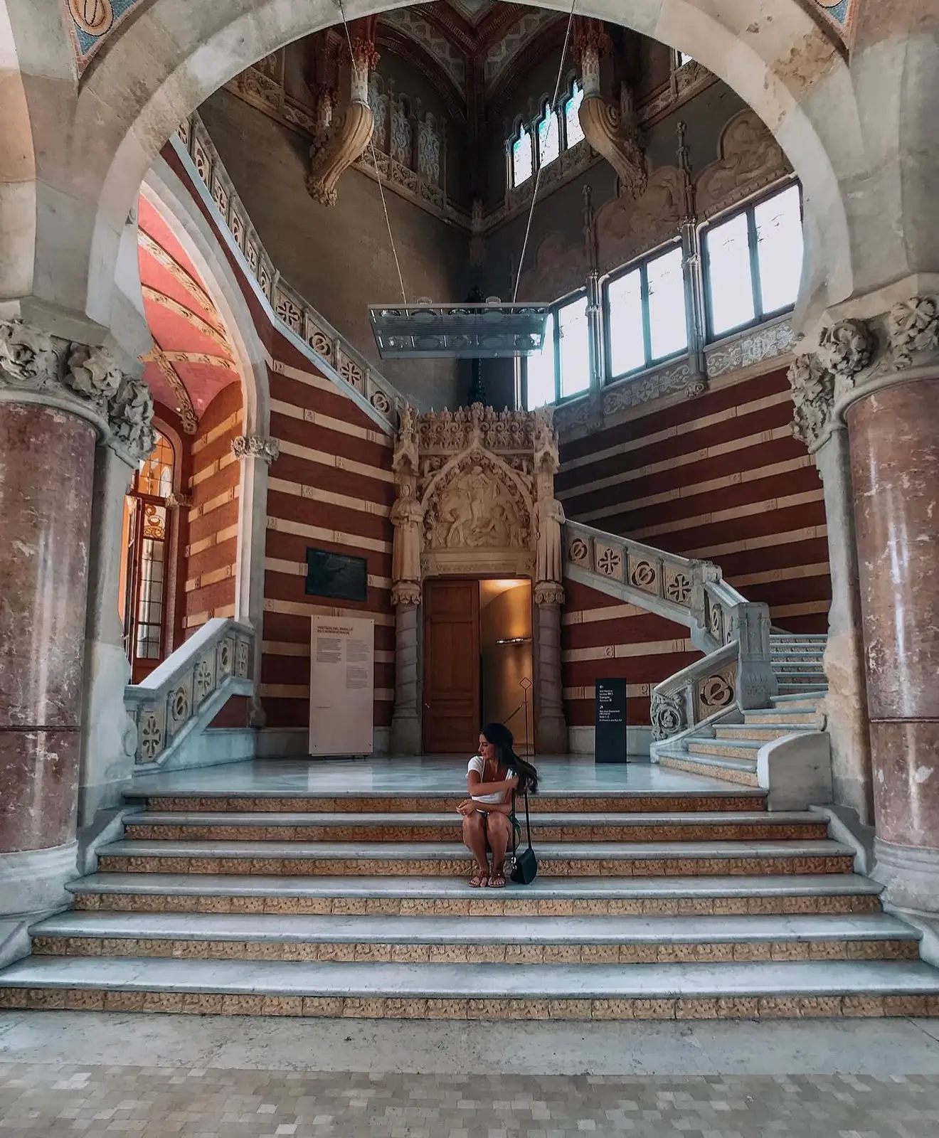 Lucia on the marble stairs of a historic Barcelona building