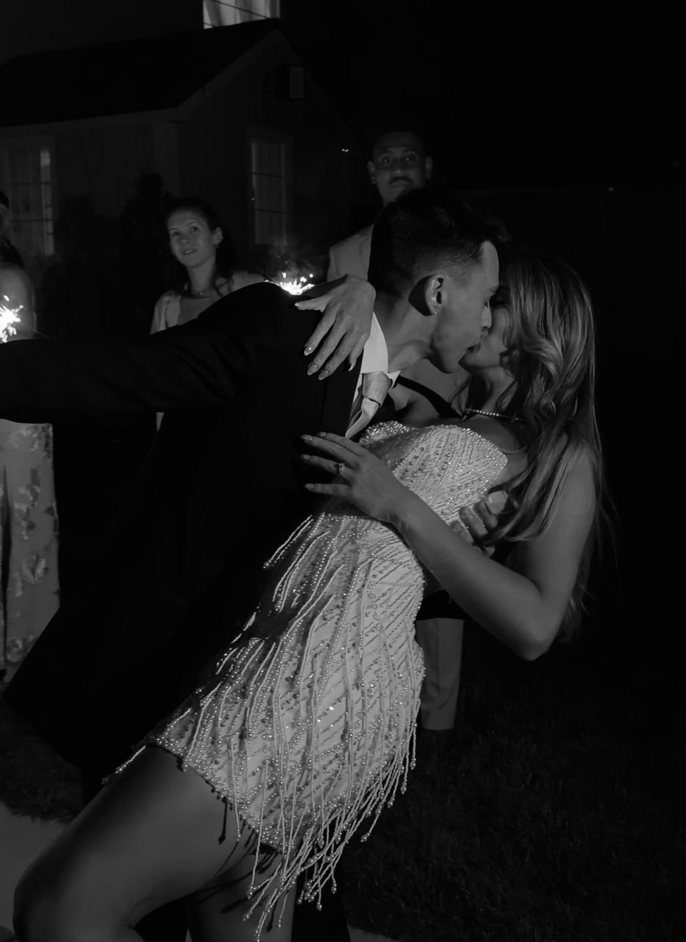 Black and white photo of the couple kissing in a sparkler send-off