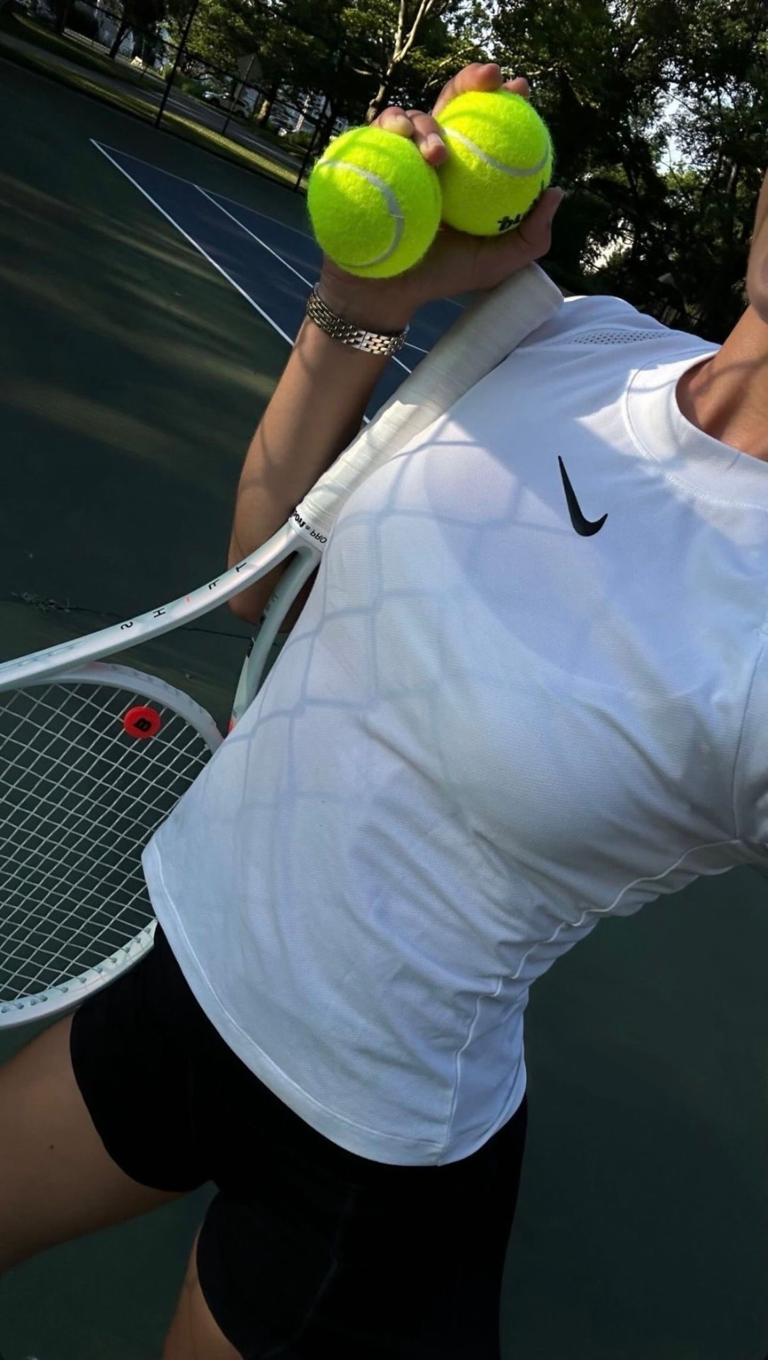 Tennis player holding two balls and a racquet in golden light