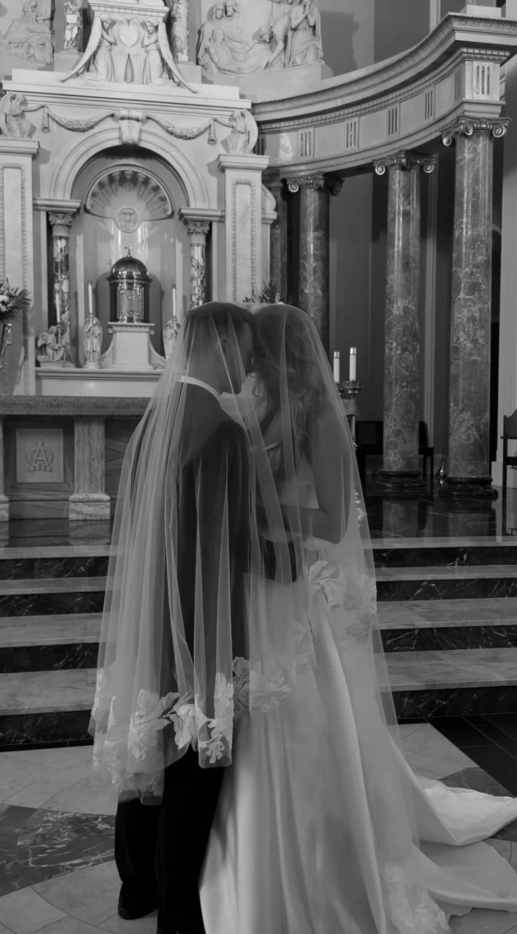Couple kissing beneath the veil on the altar steps