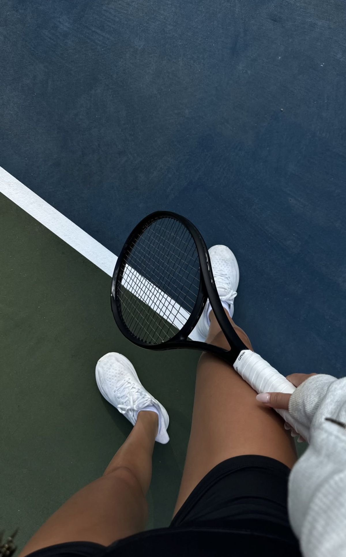 Overhead view of tennis shoes and racquet on the baseline