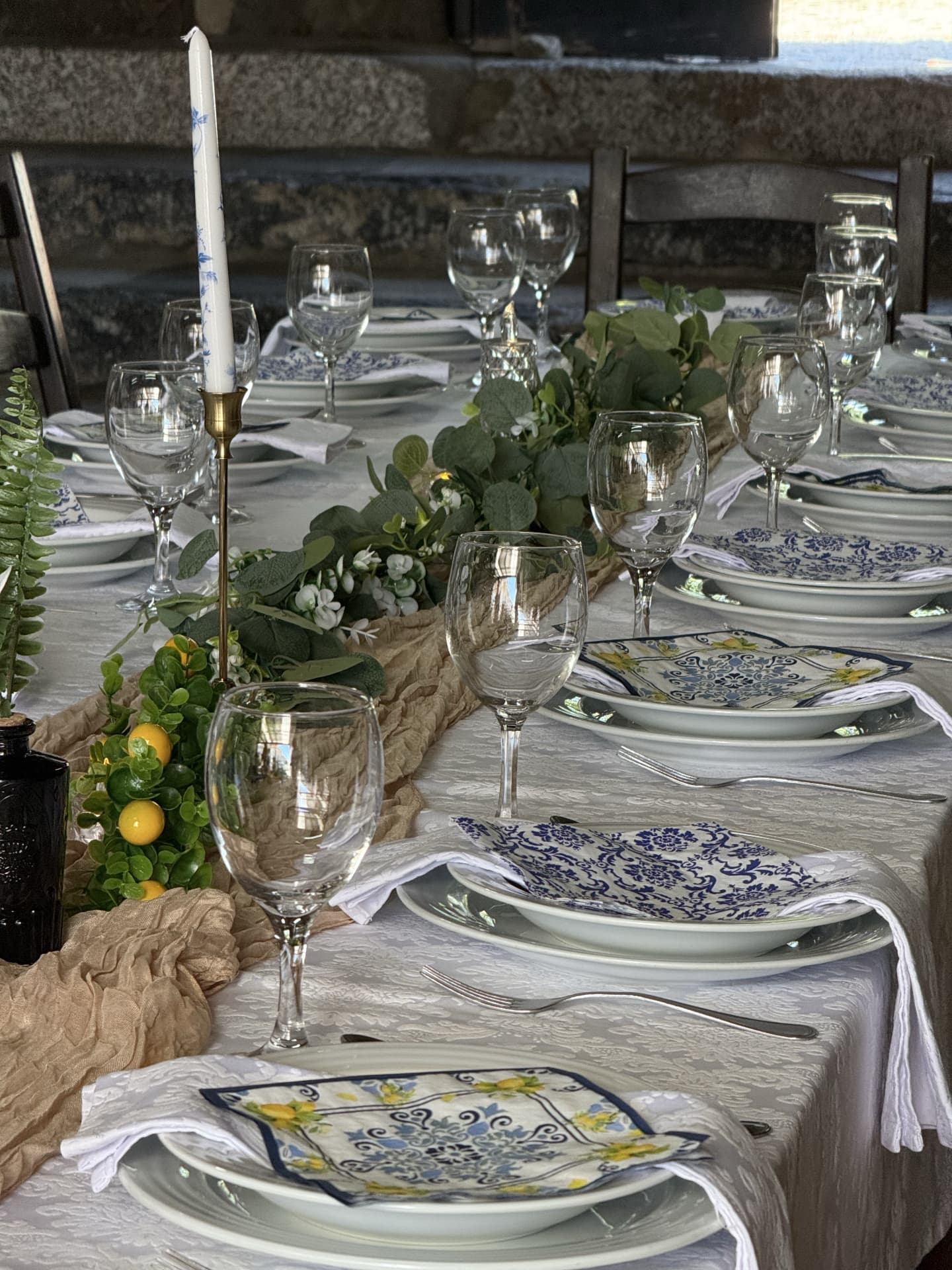 Long reception table set with blue and white patterned napkins, greenery and taper candles