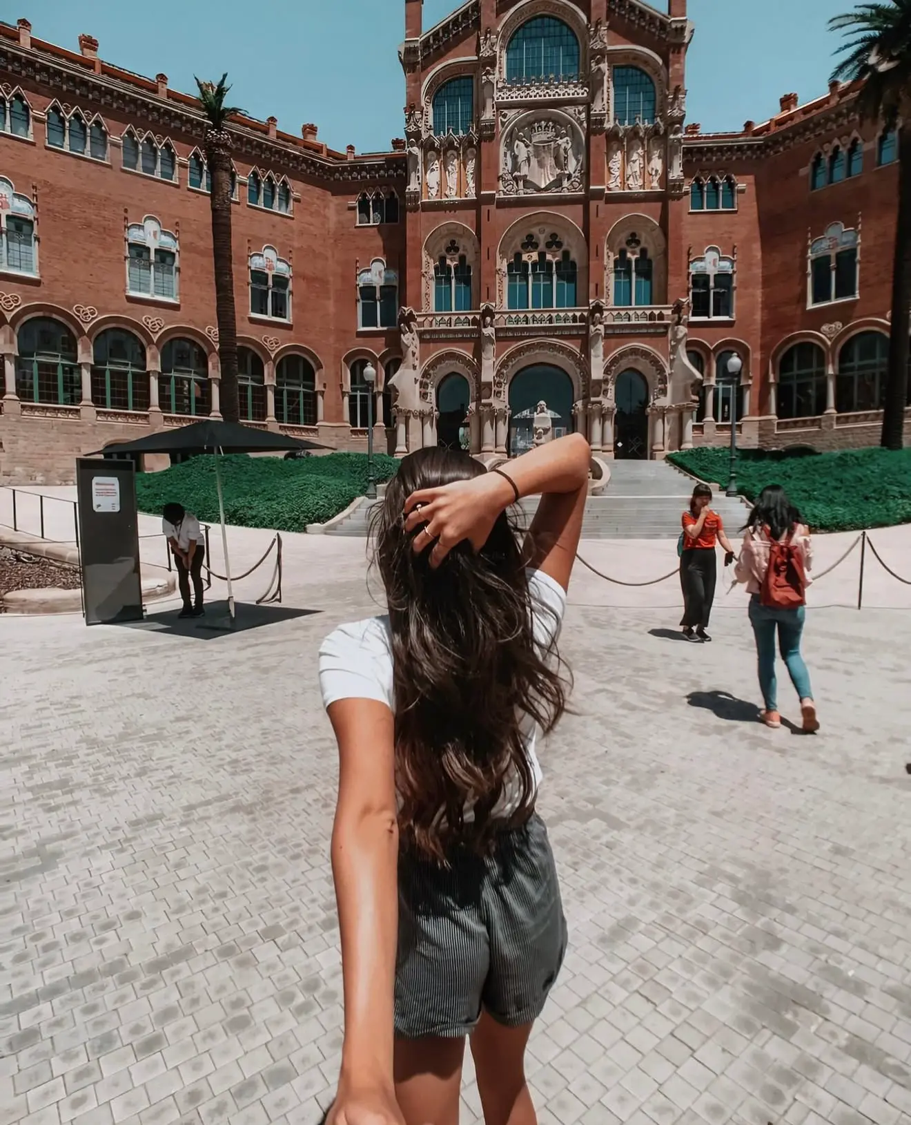 Lucia walking toward a red brick modernist building