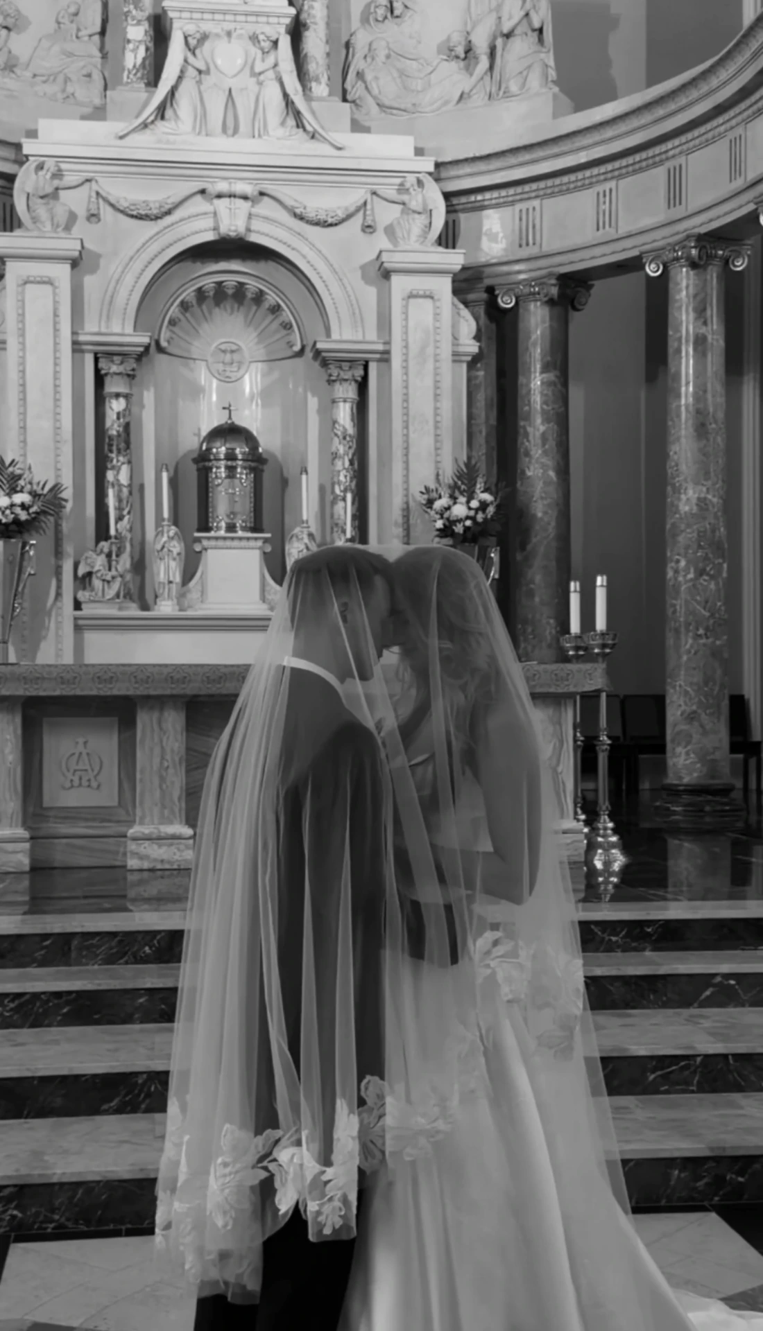 Couple kissing beneath the veil at the altar