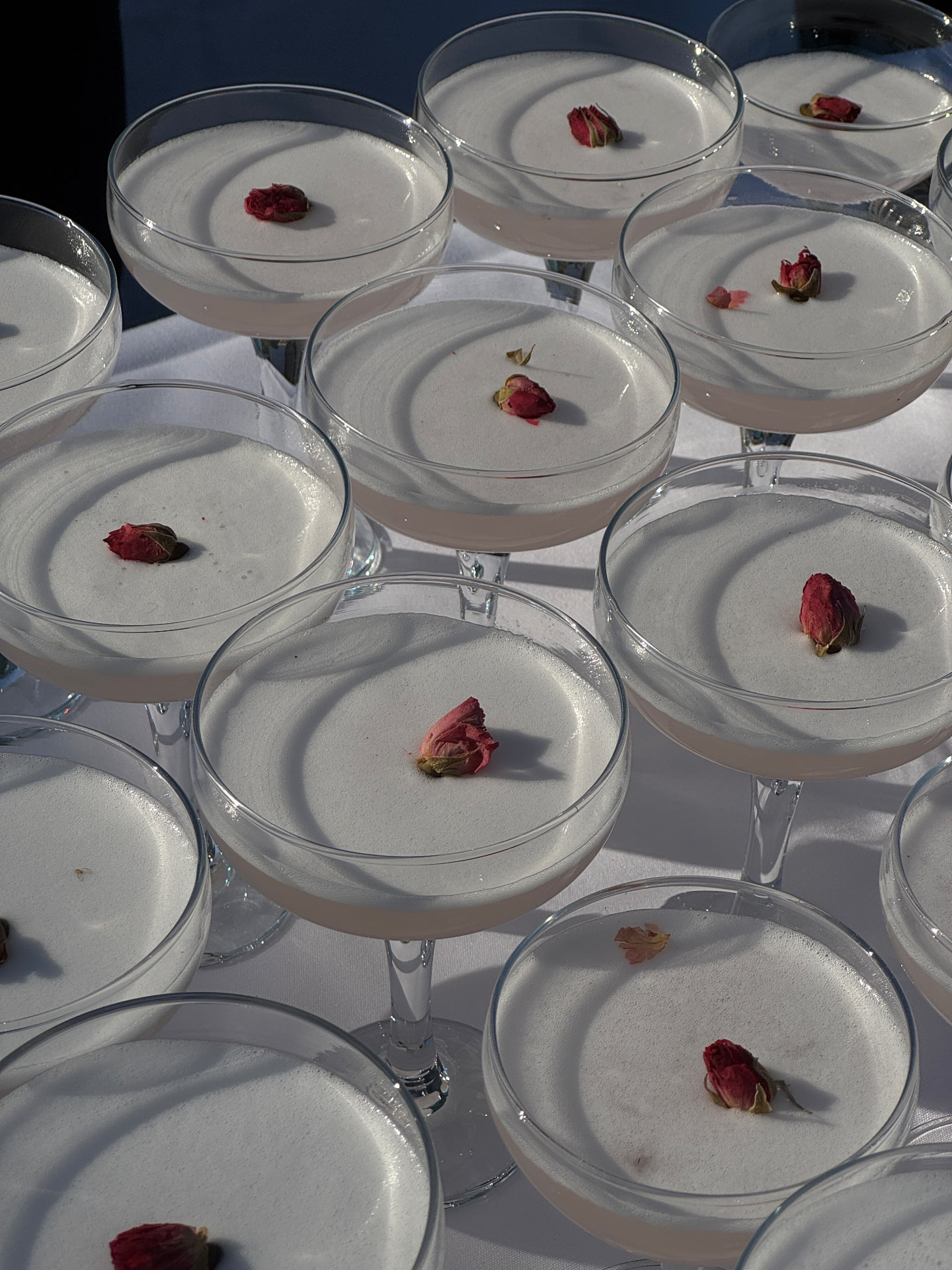 Coupe glasses of signature cocktails topped with dried rosebuds