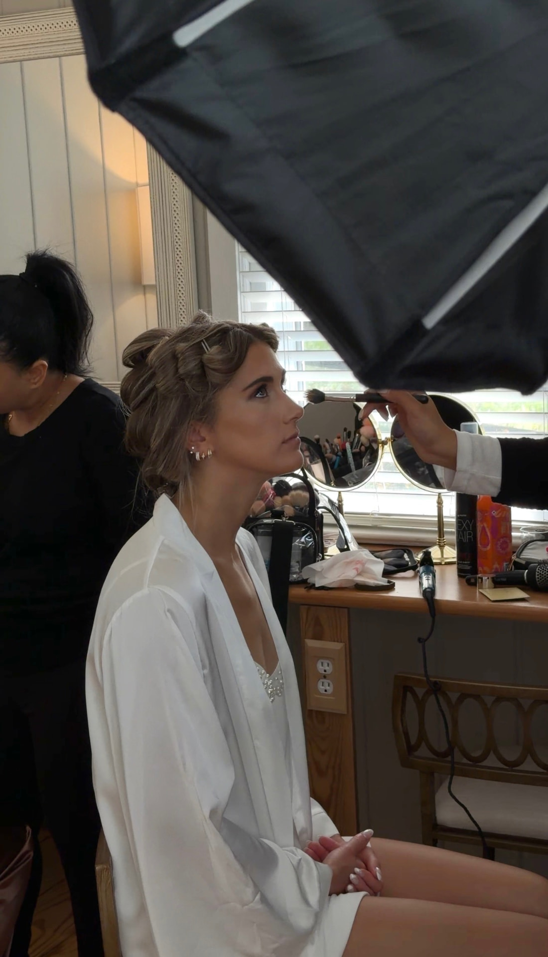 Bride in the makeup chair beneath studio light