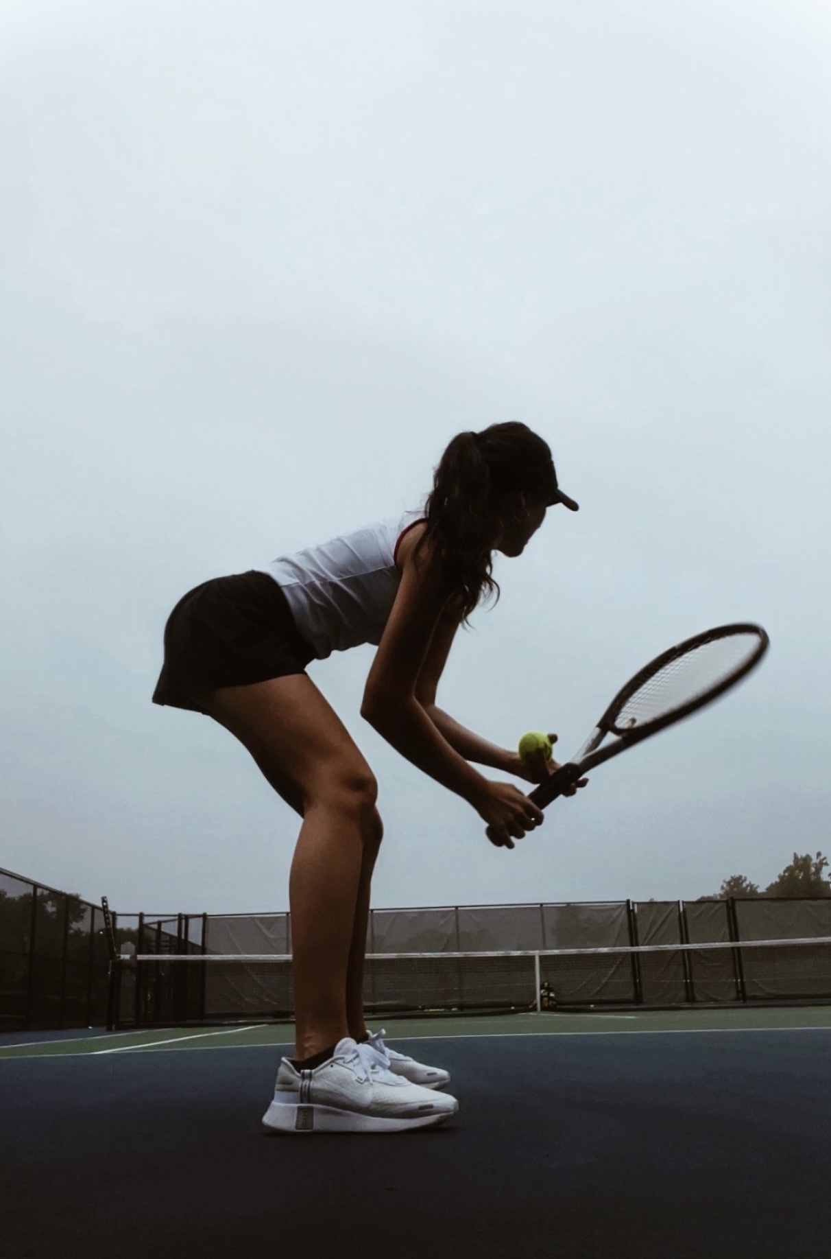 Lucia ready to serve on the tennis court at dusk