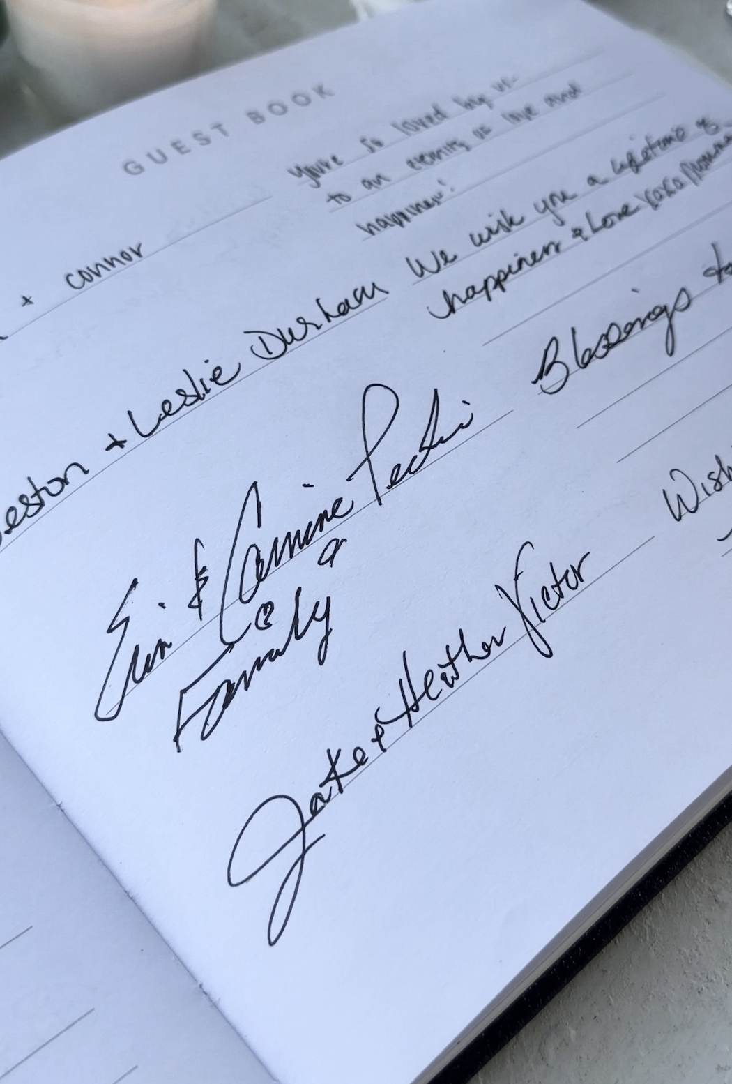 Guest book page filled with handwritten notes beside a candle