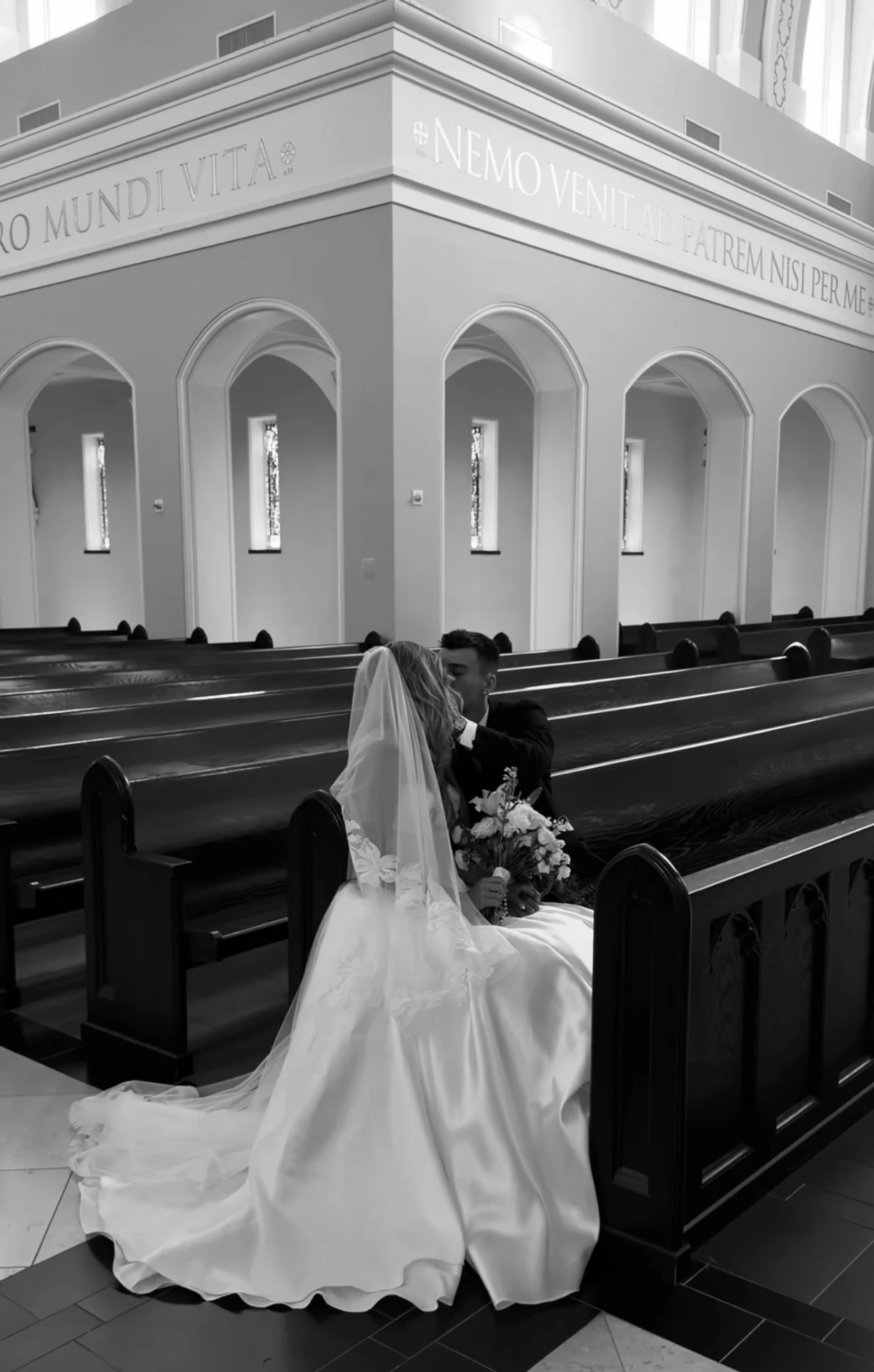 Bride and groom kissing in the church pews