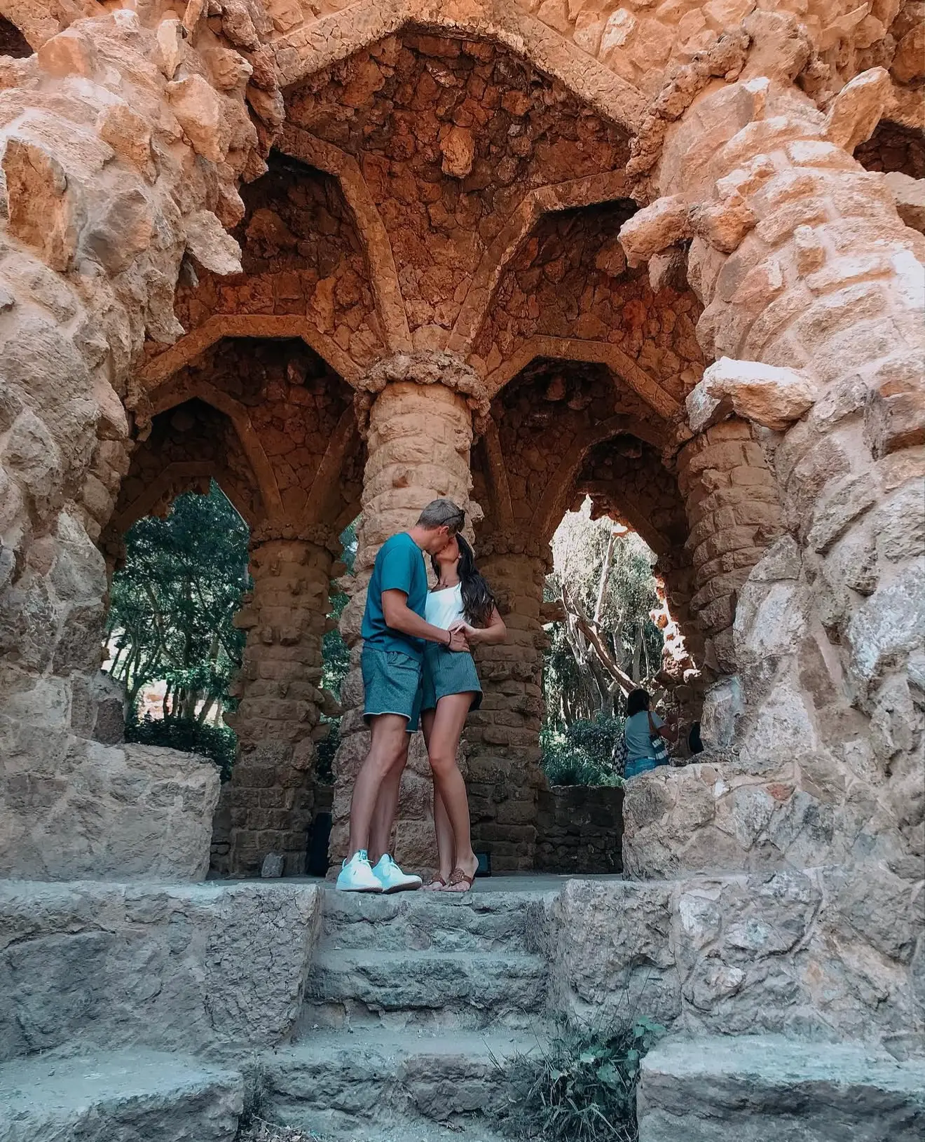 Couple kissing beneath the stone arches of Park Güell in Barcelona