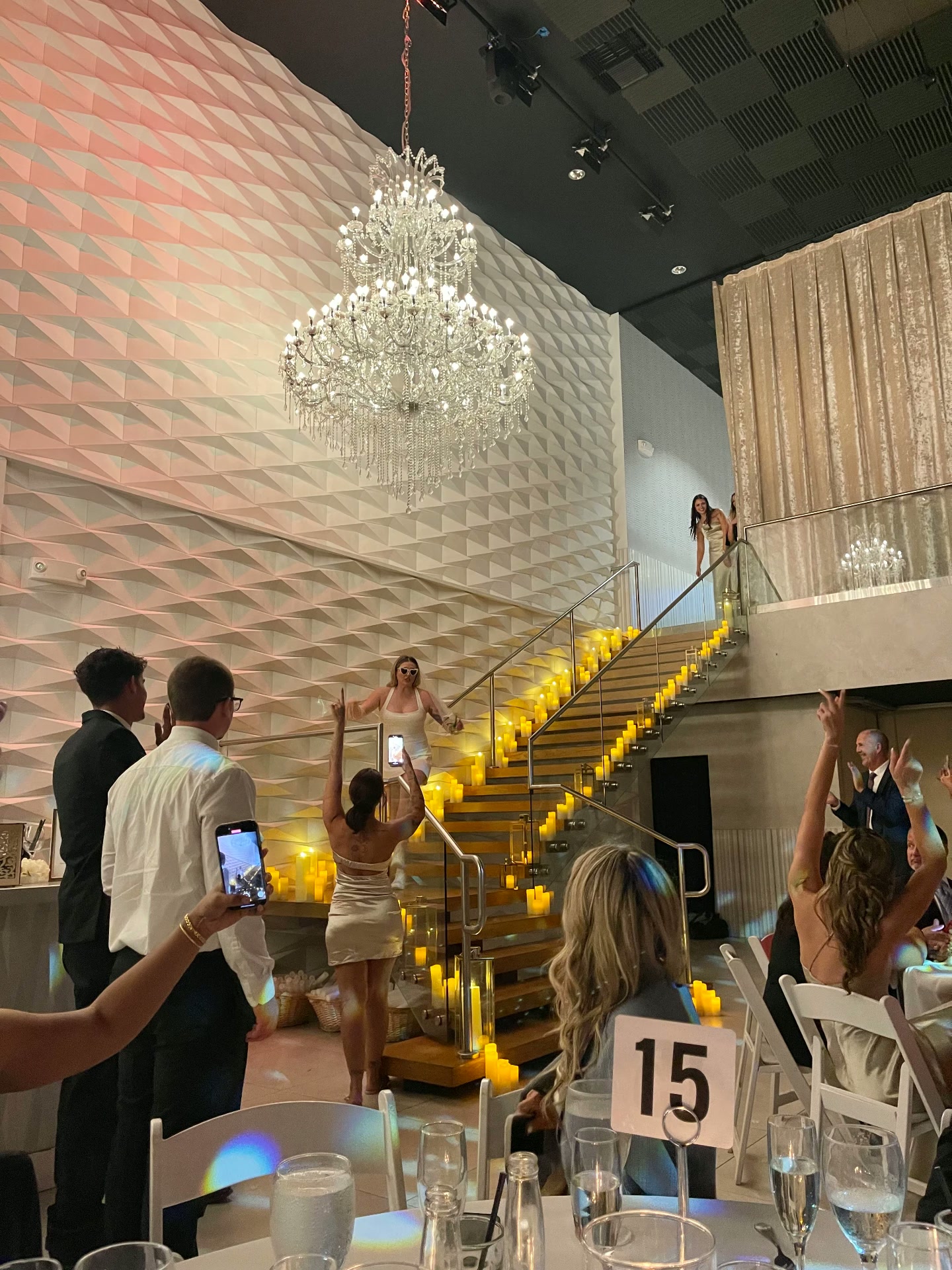 Bridal party entrance down a candlelit staircase under a chandelier