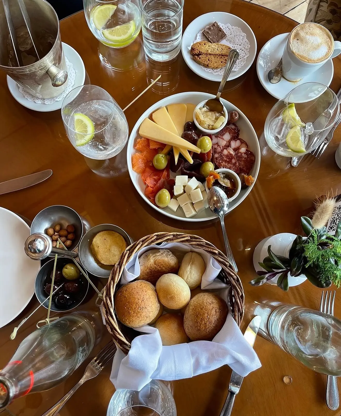 Overhead table of charcuterie, olives, fresh bread and drinks