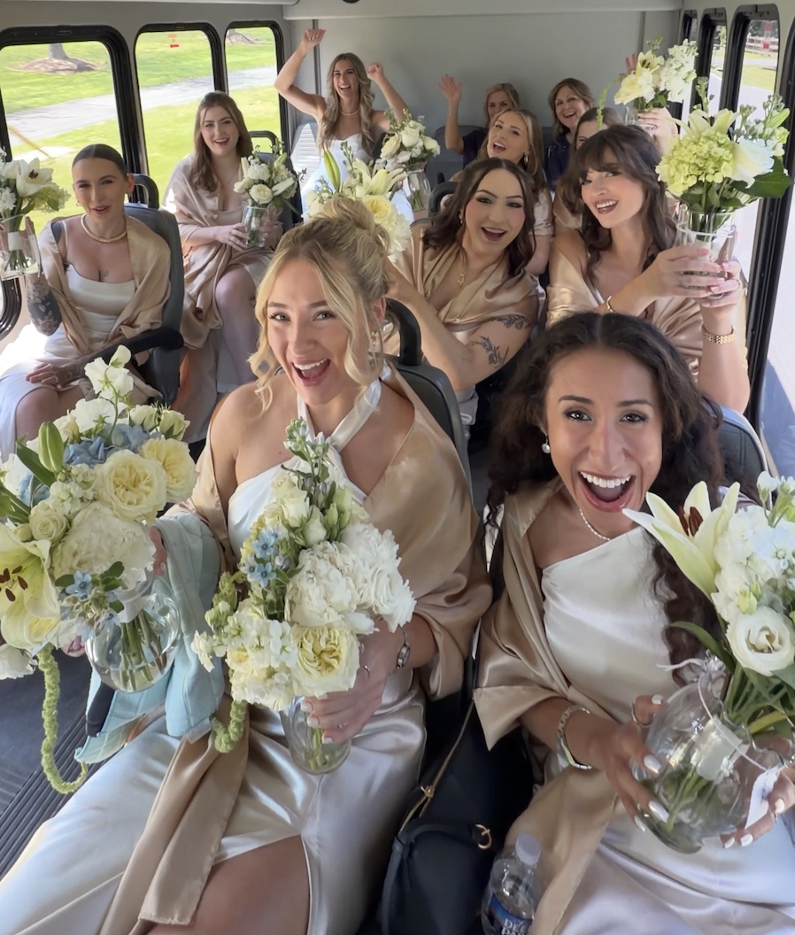 Bridal party cheering with bouquets on the shuttle bus